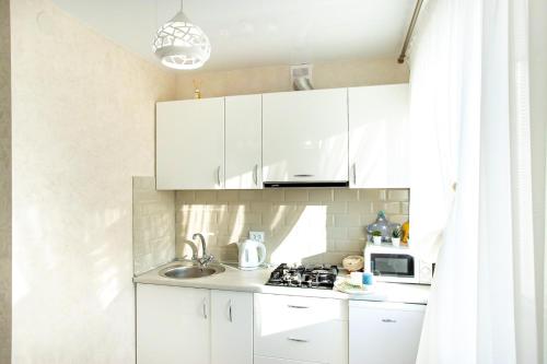 a small kitchen with white cabinets and a sink at Студия Luxury в центре in Mykolaiv
