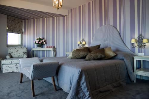 a bedroom with a large bed and a chair at Aquila Porto Rethymno in Rethymno Town