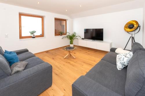 a living room with two couches and a flat screen tv at Panorama-Juwel Alpbachtal in Reith im Alpbachtal