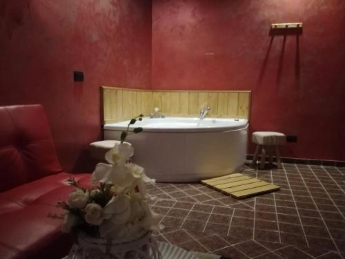 La salle de bains est pourvue d'une baignoire et d'un mur rouge. dans l'établissement La Casetta Rossa, à Frosinone