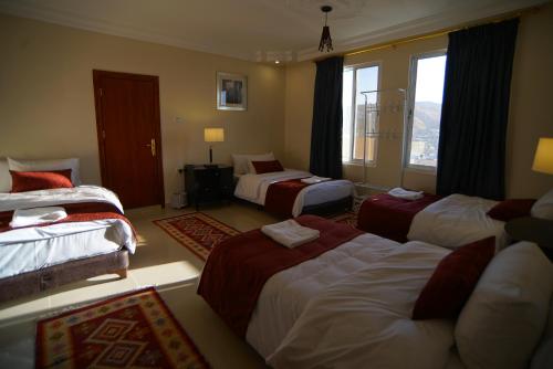 a hotel room with three beds and a window at Over Mountains Hotel in Wadi Musa