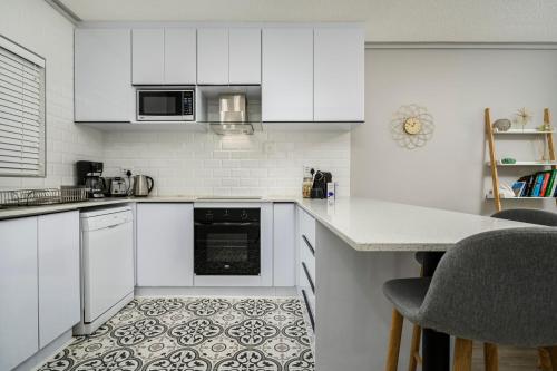 a kitchen with white cabinets and a tile floor at Brookes Hill Suites Luxury Apartment 124 in Port Elizabeth