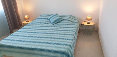 1 cama con manta de rayas azules y 2 lámparas en Ti Kaz A Rhum, en Sainte-Anne