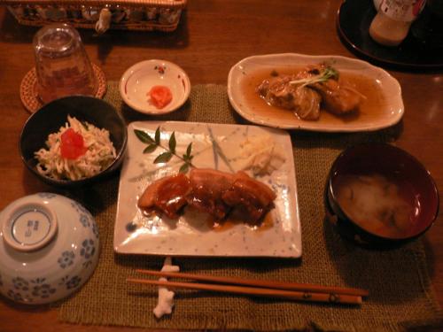 a wooden table with plates of food and chopsticks at Yufuin Country Road Youth Hostel in Yufuin