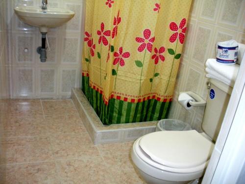 a bathroom with a toilet and a shower curtain at Hotel Casa Sarita in Bogotá