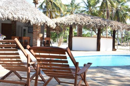 two chairs and umbrellas next to a swimming pool at Pousada Velho Bateau in Atins