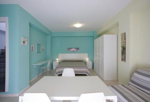Habitación con paredes azules, cama y sillas. en Appartamento Topazio, en Letojanni