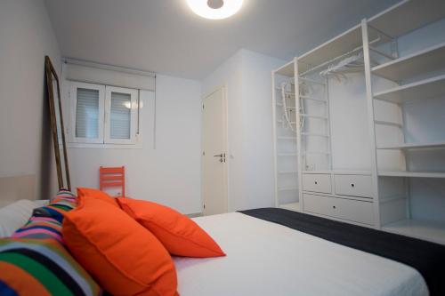 a bedroom with a bed with orange pillows and shelves at APARTAMENTO CON ENCANTO Y UBICACIÓN PERFECTA in Cádiz