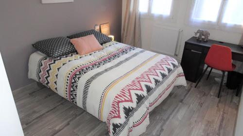 - une chambre avec un lit, un bureau et une chaise rouge dans l'établissement Grand appartement T3/T4 proche des berges du Cher, à Montluçon