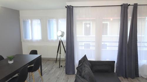 - un salon avec un canapé, une table et des fenêtres dans l'établissement Grand appartement T3/T4 proche des berges du Cher, à Montluçon