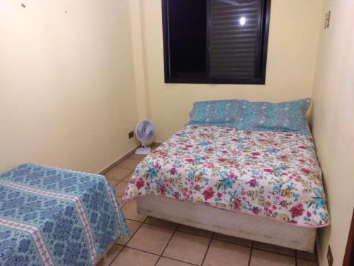 a small bedroom with a bed and a window at Apartamento "Pé na Areia" Mongaguá in Mongaguá