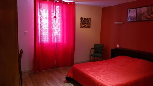 een rode slaapkamer met een rood bed en een rood gordijn bij La Roseraie in Épinal