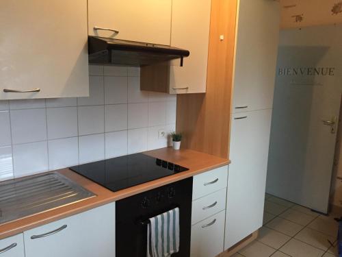 La cuisine est équipée de placards blancs et d'un four avec plaques de cuisson noires. dans l'établissement Maison 2ch - 4 pers en Picardie parking gratuit by La Source d'OrFée, à Courcelette