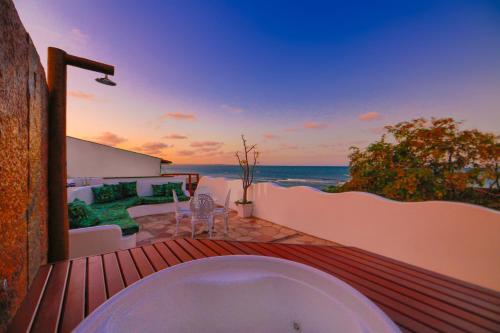 a bath tub on a deck with a view of the ocean at Encanto das Flores in Pipa