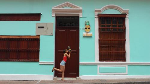 a woman is standing in front of a blue building at La Vaina Cali in Cali