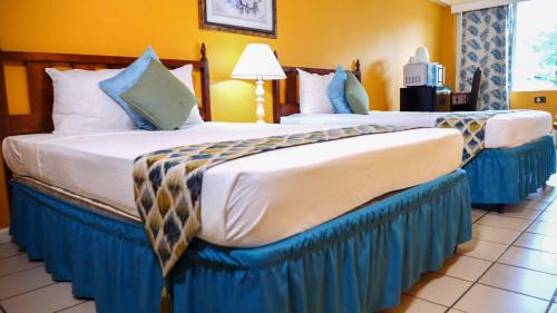 two beds in a hotel room with blue skirts at Pineapple Court Hotel in Ocho Rios