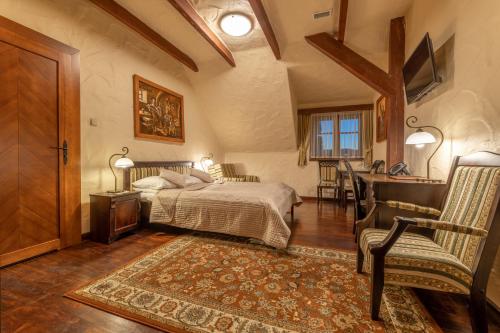 a bedroom with a bed and a desk and a chair at Hotel Stanica Kresowa Chreptiów in Lutowiska