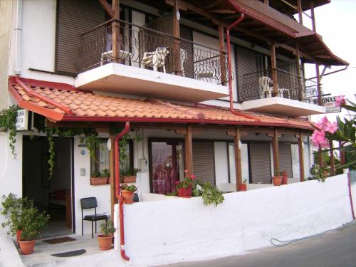 a building with potted plants and a balcony at Vassilis Guesthouse in Raps&aacute;ni