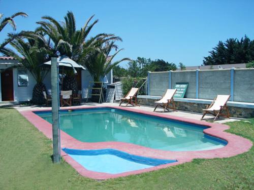 uma piscina com duas cadeiras e uma palmeira em Hotel y Cabañas La Rosa Nautica em Pichidangui