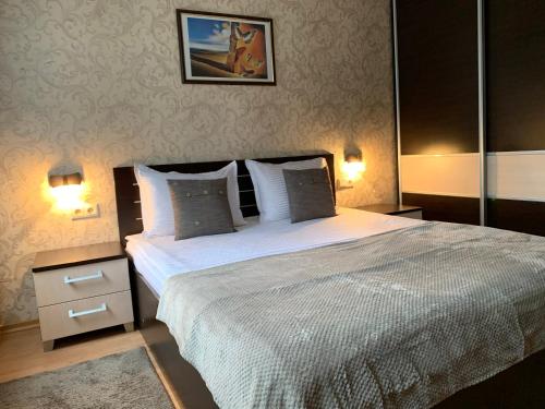 een slaapkamer met een groot bed en 2 lampen bij GM Royal Plaza in Borovets