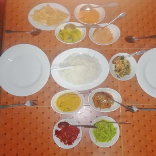 a table topped with white plates and bowls of food at Sudumal Cottage in Ella