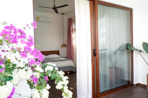a room with a bed and a glass door with flowers at Casa Beu in Puerto Escondido