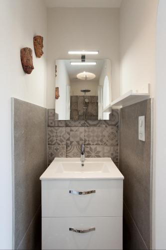 une salle de bain avec un lavabo blanc et un miroir dans l'établissement Maison de village provencal avec piscine, à Fontvieille