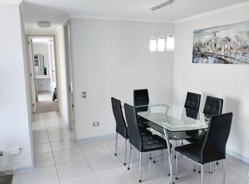 a dining room with a glass table and black chairs at Vista Chinchorro in Arica