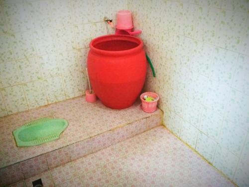 a red bucket sitting on the corner of a bathroom at Budaya Kaki Rinjani in Senaru