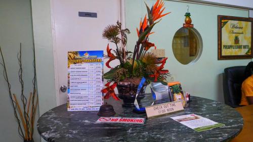 a table with a vase of flowers on it at Pineapple Court Hotel in Ocho Rios