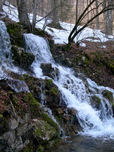 a waterfall on the side of a hill with snow at Rifugio Monte Baldo in Avio