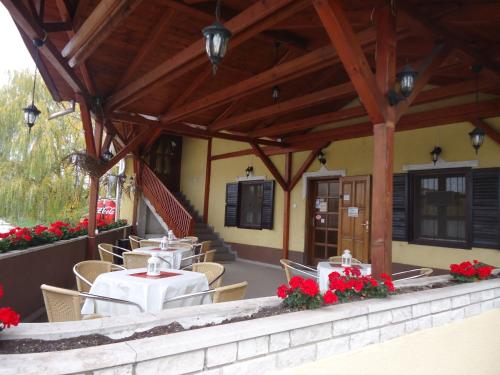 a restaurant with tables and chairs and red flowers at Czermann Panzió és Étterem in Oroszlány