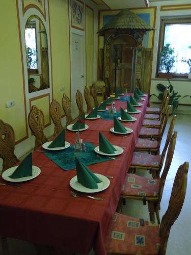 a long table with green napkins and plates on it at Czermann Panzió és Étterem in Oroszlány