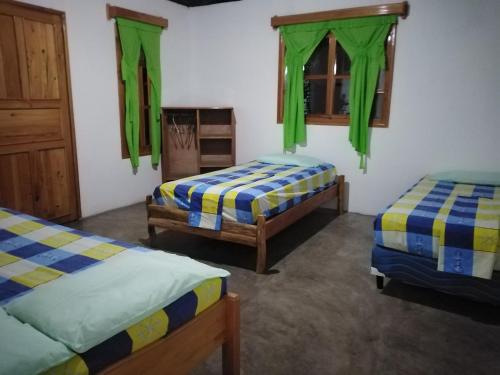 a room with two beds and green curtains at Bungalows Familiares in Monterrico