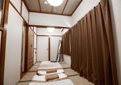 eine Reihe von Betten in einem Zimmer mit Vorhängen in der Unterkunft カビラハウス Kabira House 窓から見える川平湾まで徒歩1分 in Ishigaki-jima