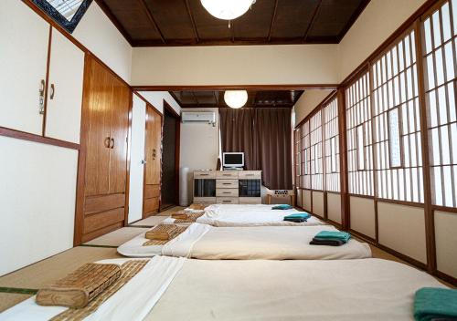 eine Reihe von Betten in einem Zimmer mit Fenstern in der Unterkunft カビラハウス Kabira House 窓から見える川平湾まで徒歩1分 in Ishigaki-jima