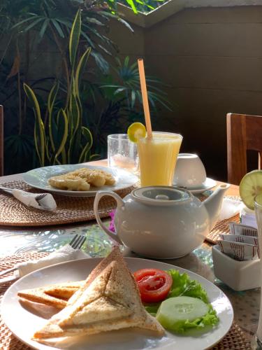 a table with a plate with a sandwich and a drink at Kukuh House Ubud in Ubud