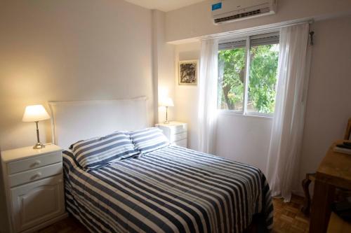 um quarto com uma cama com um cobertor listrado e uma janela em Departamento en Belgrano em Buenos Aires