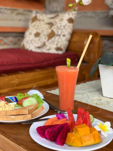 a table with two plates of food and a drink at Kukuh House Ubud in Ubud