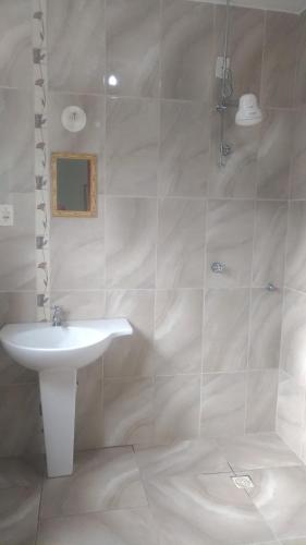 a white bathroom with a sink and a shower at Pousada da Iza in Itatiaia