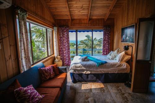 a bedroom with a bed and a couch and a window at Marazul Paradise Beach House- Panoramic Ocean Views in Vincentia