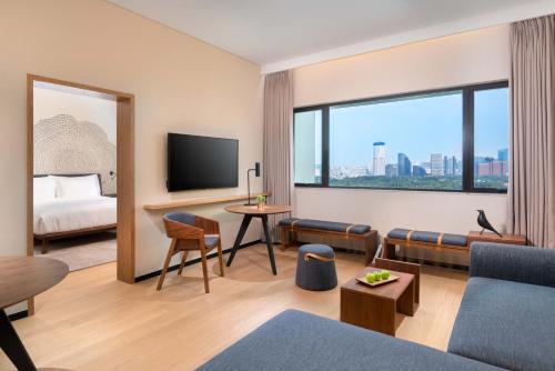 a hotel room with a couch and a tv and a bed at BEI Zhaolong Hotel, JdV by Hyatt in Beijing