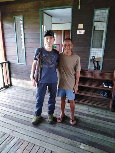 two men are standing on a wooden deck at AA Homestay in Mulu