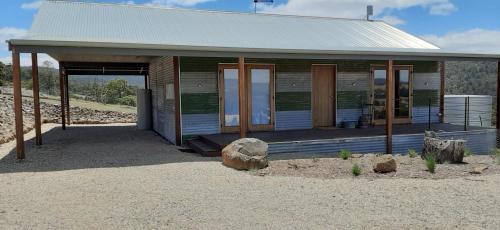 a small wooden building with a porch in the desert at Fellcroft Farmstay in Cobaw