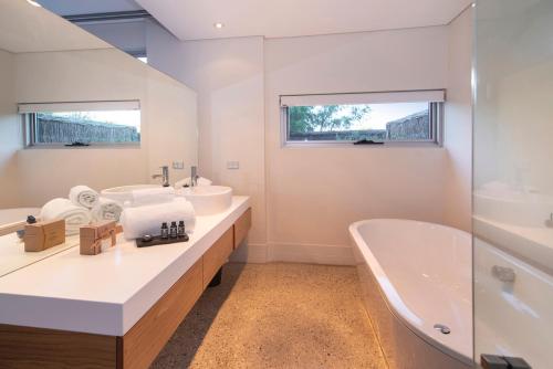 a white bathroom with two sinks and a tub and a bath tubermott at Smiths Beach Resort in Yallingup