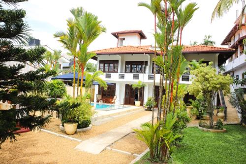 a villa with a swimming pool and palm trees at Sky and Sand Guesthouse in Beruwala