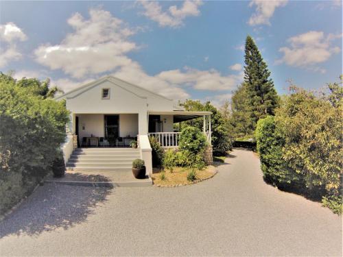 a white house with a porch and a driveway at Swellendam Country Lodge - Guest House - B&B in Swellendam