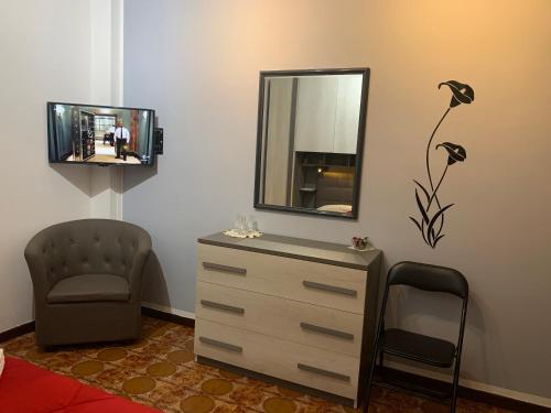 una camera da letto con cassettiera, specchio e sedia di AndEli ad Alghero