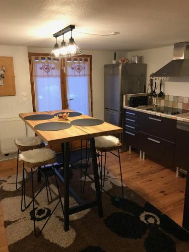- une cuisine avec une table en bois et des tabourets dans l'établissement le coin tranquille, à Aime La Plagne