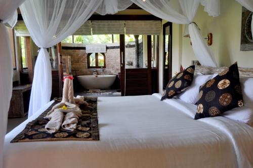 a bedroom with a bed with a bath tub and a tub at Subak Tabola Villa in Sidemen